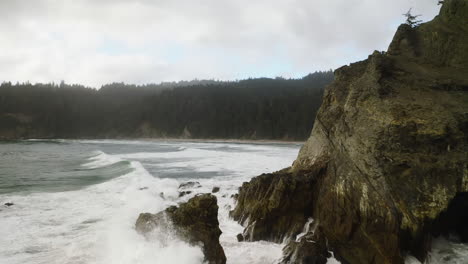 Fast,-low-flight-past-jagged-cliffs,-powerful-Pacific-Ocean-waves,-Oregon-Coast