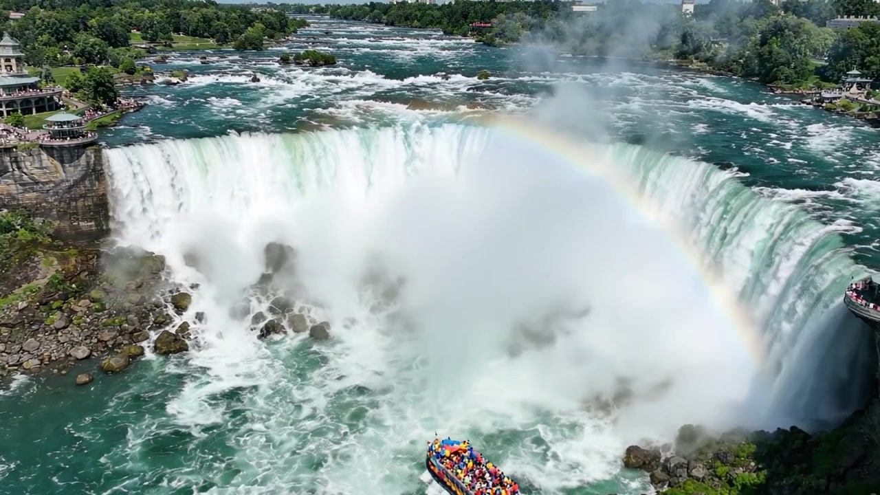 A Spectacular View of a Majestic Waterfall with a Vibrant Rainbow, Encompassing Nature's Beauty and the Thrill of Boating Adventures Nearby