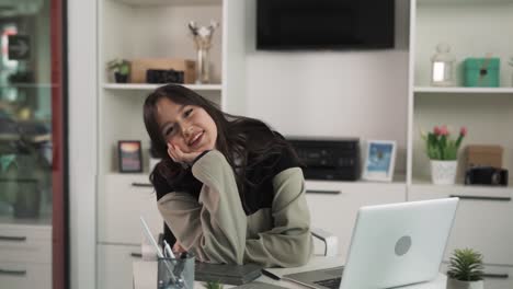 The-portrait-depicts-a-young-dark-haired-woman-who-smiles-and-speaks-into-the-camera,-making-the-"class"-gesture