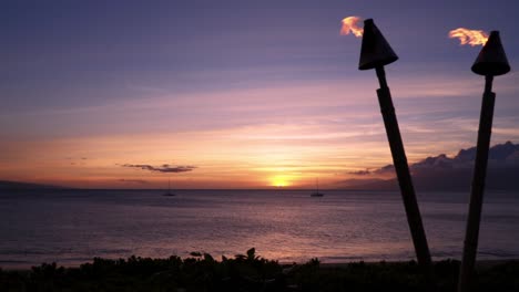 Vista-De-La-Puesta-De-Sol-En-Una-Playa-En-Maui-Con-Antorchas-De-Fuego