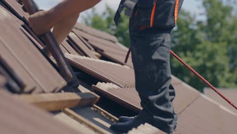 roofer working on roof using safety rope, removing tiles