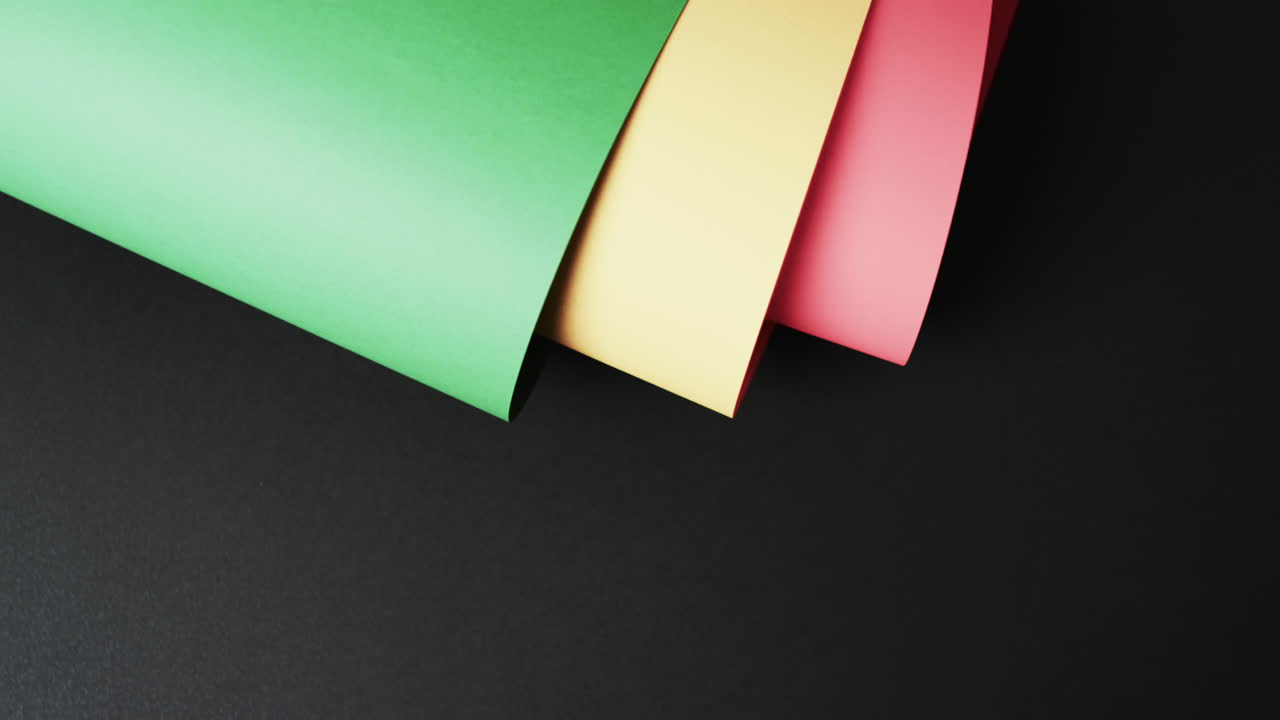 검은색 배경에 복사 공간을 가진 빨간색, 노란색 및 녹색 종이를 굴러 넣은 비디오