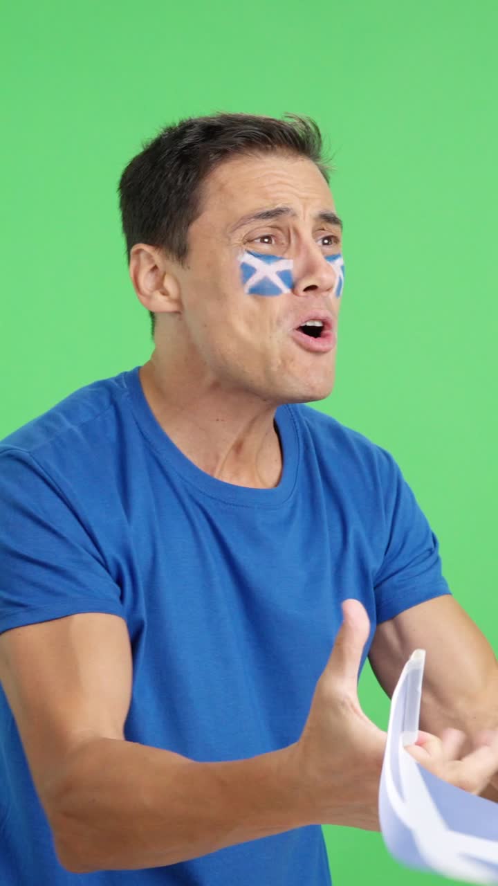 Nervous man cheering for Scotland during a match looking away