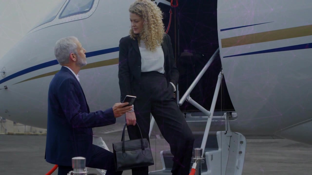Uomo che tiene in mano il telefono mostrando un passaggio animato di un jet mentre una donna scende confermando i dettagli del viaggio