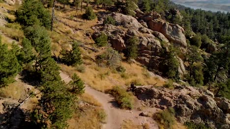 Drone-shot-of-mountainous-terrain,-hikers-and-cityscape-in-the-distance