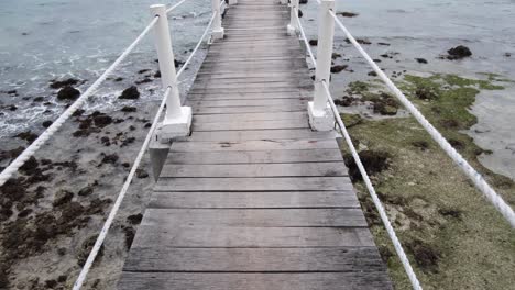 muelle de madera en una playa rocosa en una isla tropical
