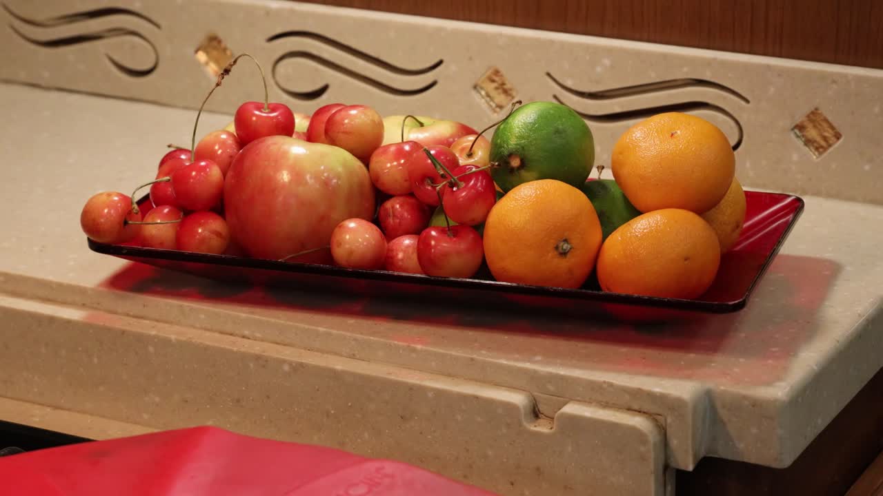 작은 카운터에 앉아 있는 동안 과일로 가득 찬 빨간 접시 - 루핑