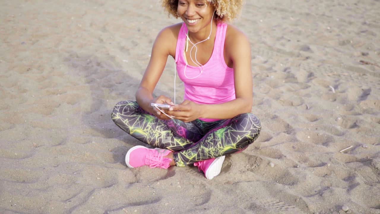 mujer sentada en la playa escuchando musica