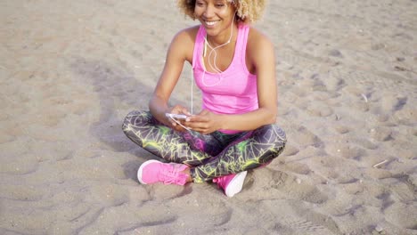 Woman-sitting-at-beach-listening-to-music