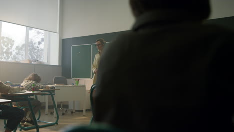 estudiantes sentados en escritorios en el aula. maestro explicando la lección a los alumnos