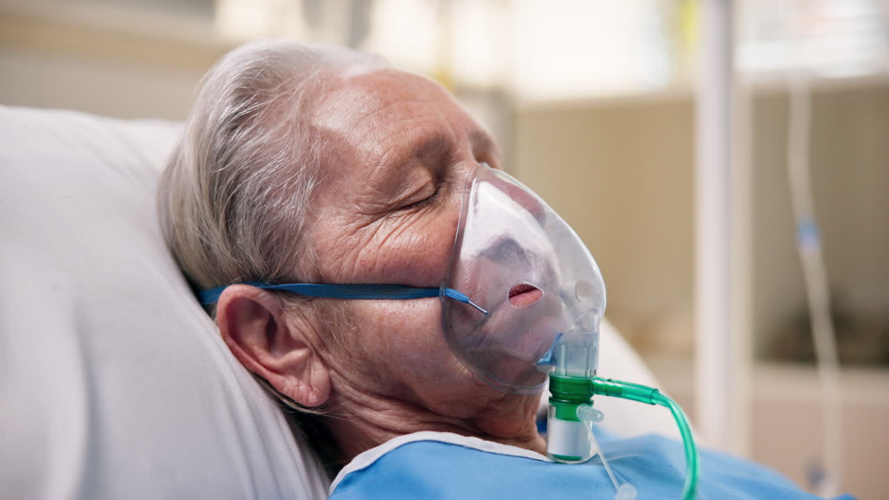Elderly patient with oxygen mask in hospital bed