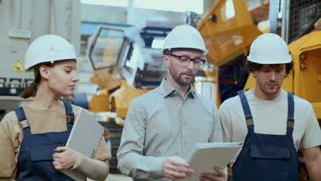 industrial engineer instructing factory workers in production hall