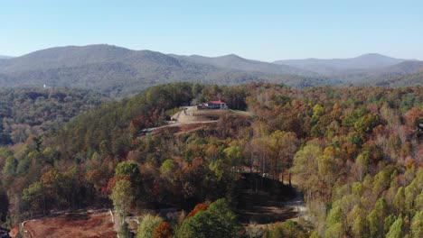 Drohnenaufnahme-Einer-Einsamen-Hütte-Auf-Einem-Hügel-Inmitten-Der-Herbstfarben-In-Helen,-Georgia