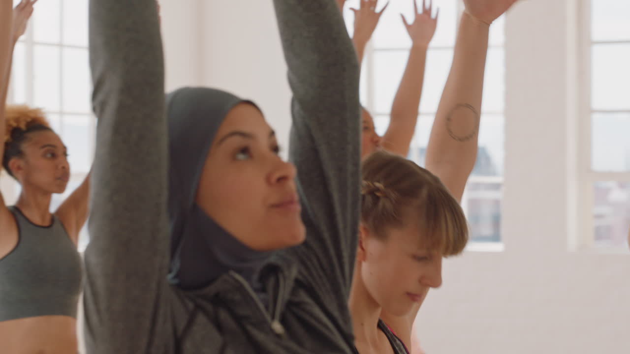 yoga class instructor teaching warrior pose to young caucasian woman exercising enjoying healthy lifestyle in fitness studio practicing posture