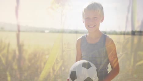 Animation-of-plants-and-sunlight-over-happy-caucasian-schoolboy-with-football-in-field