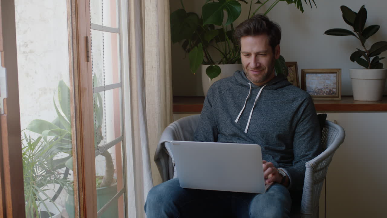 young man using laptop computer working from home browsing online watching entertainment enjoying relaxing on weekend