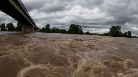 flooded river under bridge in stormy weather