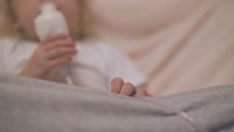 girl with inhaler lies in bed in light room focus on hand