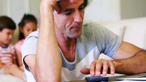 Tense-man-using-calculator-in-living-room