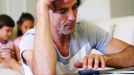hombre tenso usando una calculadora en la sala de estar