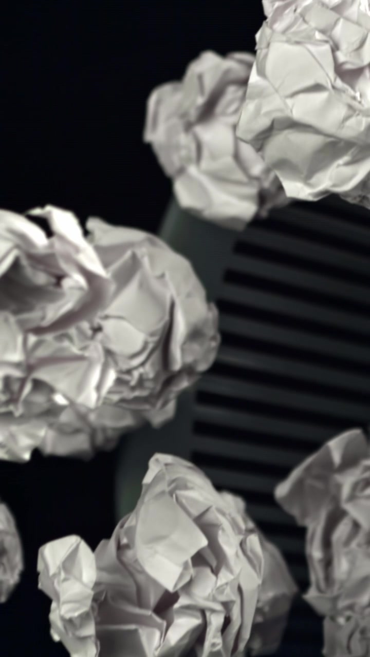 White Crumpled Paper Falling into a Waste Bin on Dark Background