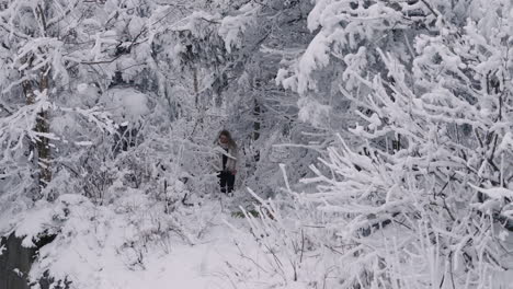 woman walking at wilderness with snow covered tree branches and foliage in orford, quebec, canada