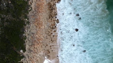 Olas-Espumosas-Chocando-Contra-Una-Costa-Rocosa,-Vista-Desde-Un-Dron-Arriba