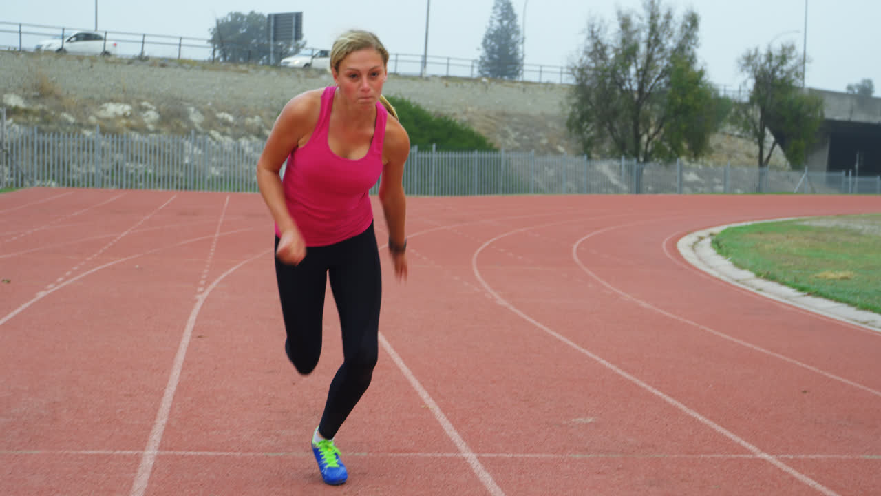 vista frontal de una atleta caucásica corriendo en un lugar deportivo 4k