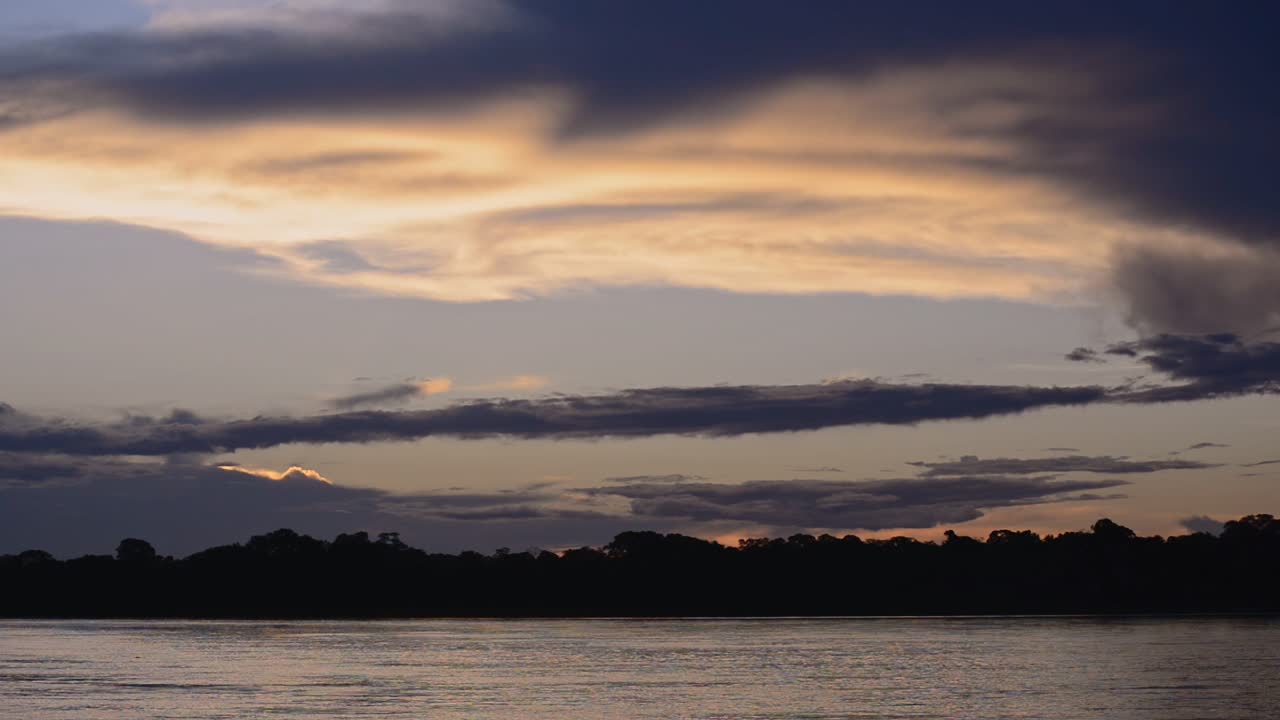 Silhouette Of Trees And The Calm Amazon River Under The Dramatic Sky On A Glorious Sunset Scenery In Peru - Wide Shot