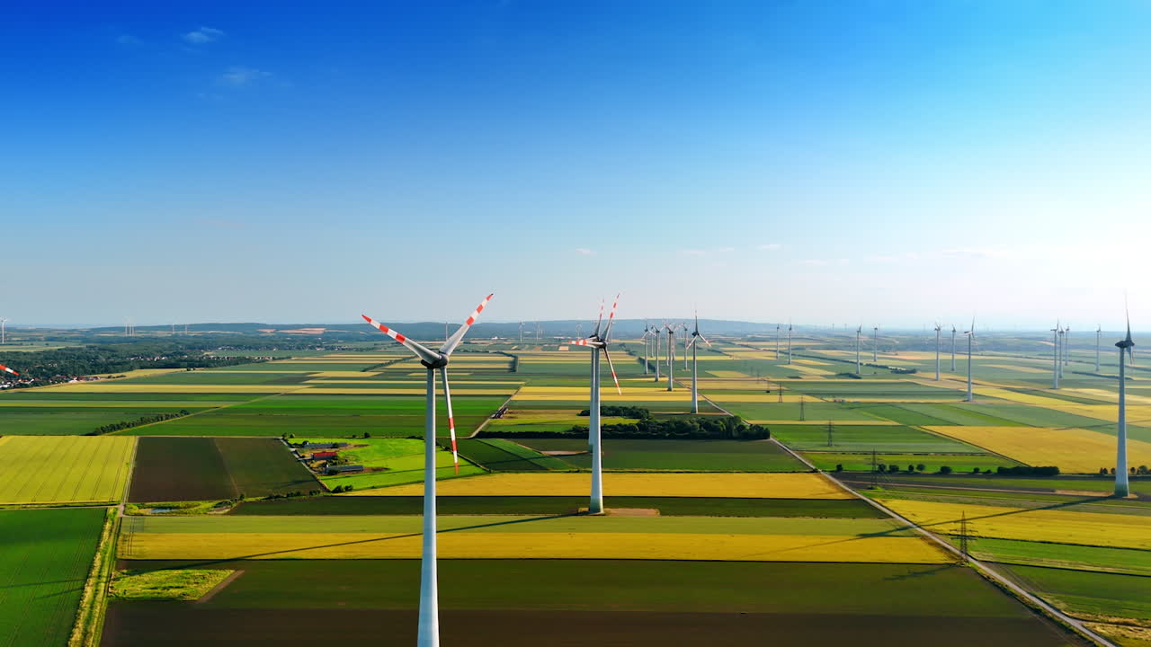 Wind turbines across Europe. Wind turbines stand tall across lush fields in Europe, showcasing renewable energy and pastoral beauty on a clear day