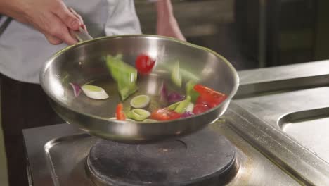chef cocinando verduras en una sartén