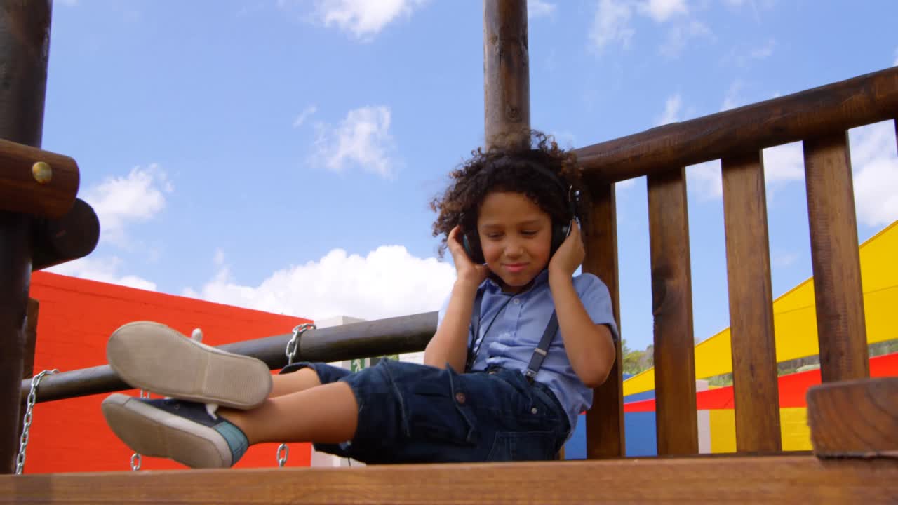 Front view of mixed-race schoolgirl listening music on headphones in the school playground 4k