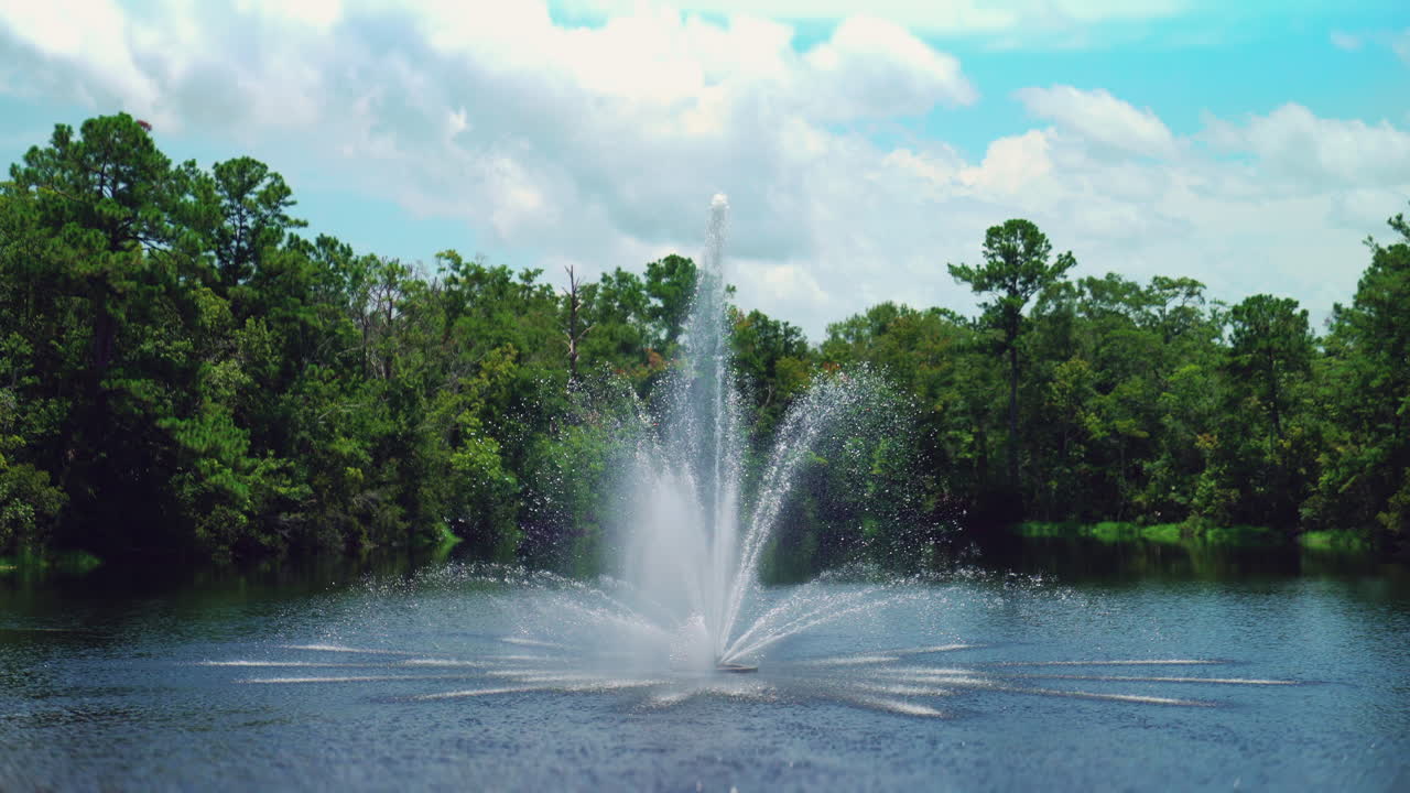 A calm scene featuring a decorative fountain surrounded by lush greenery in Florida, under a clear blue sky with some clouds. The soothing water flow contrasts with the sunny, warm atmosphere.