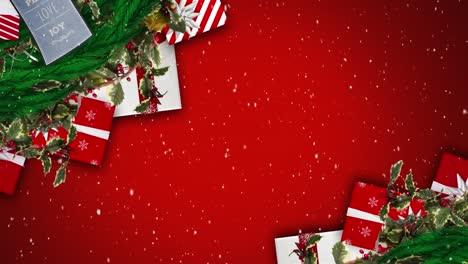 Digital-animation-of-snow-falling-against-christmas-gift-boxes-and-decorations-on-red-background