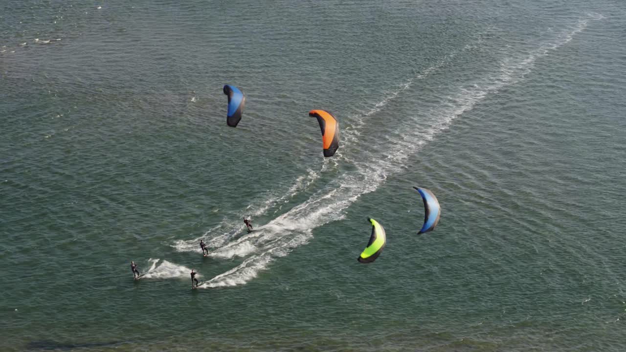 4명의 카이트 서퍼가 트위드 마스블락테의 잔잔한 네덜란드 물에서 함께 타고 있습니다.