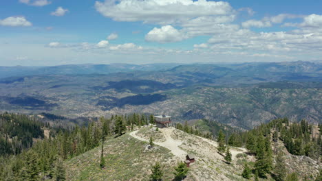 aerial passing fire lookout station on top of mountain in national forest