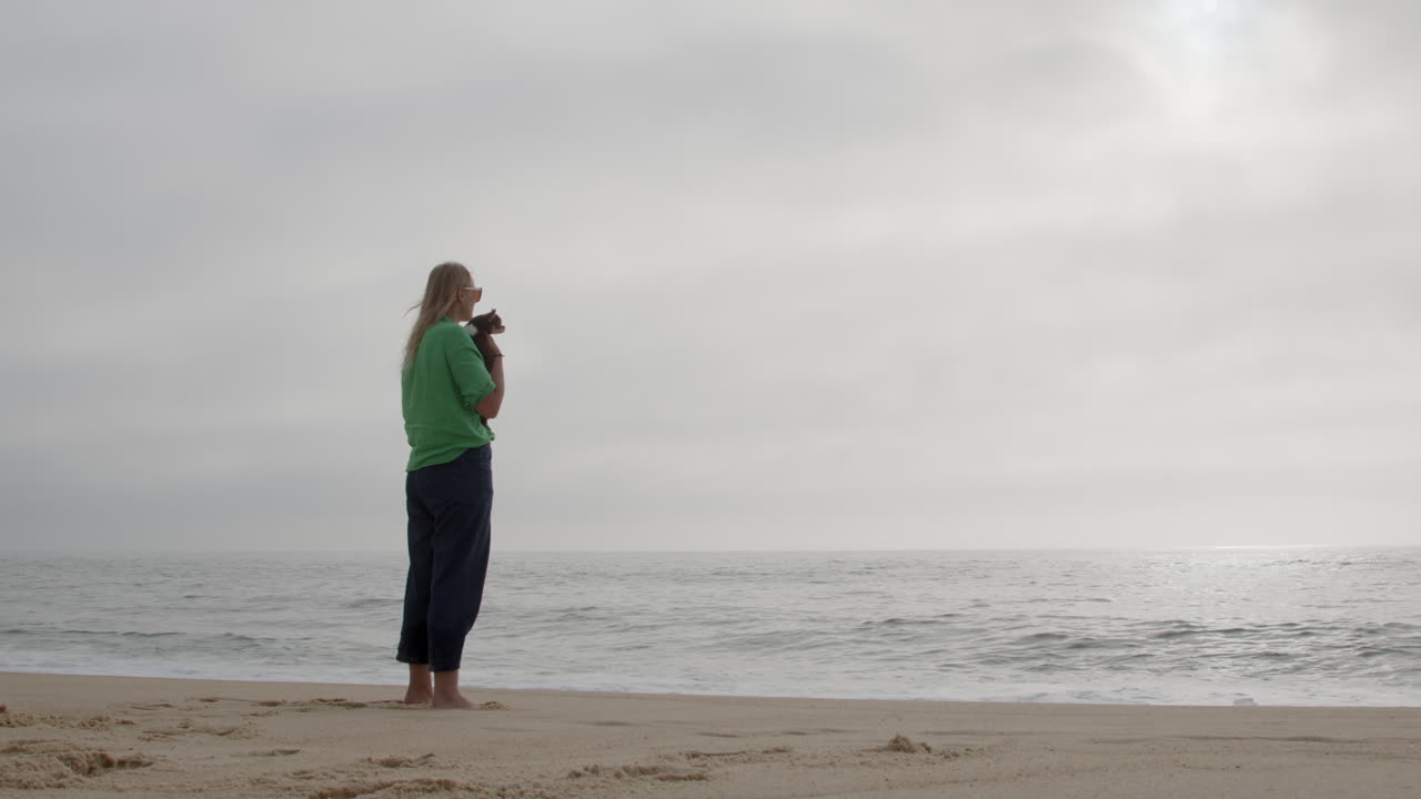 해변에 있는 개와 함께 있는 여자