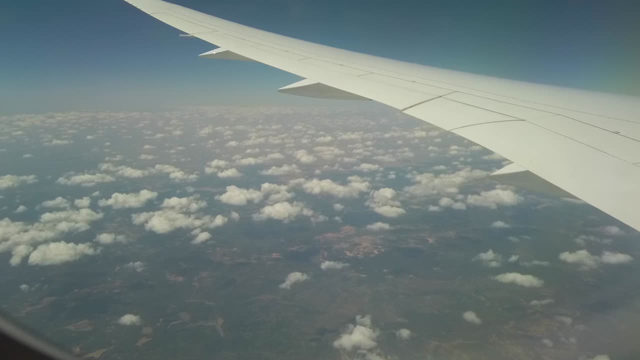 Et accelereret optagelse taget fra et flyvindue af vingen og mange små skyer