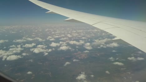 an accelerate shot taken from a window in a plane of the wing and many tiny clouds