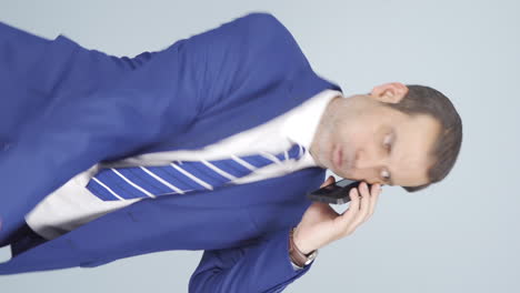 화를 내는 사업가의 수직 비디오가 전화에 있습니다.