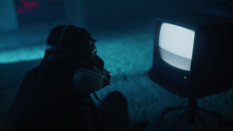 person in gas mask watching old tv in dark room