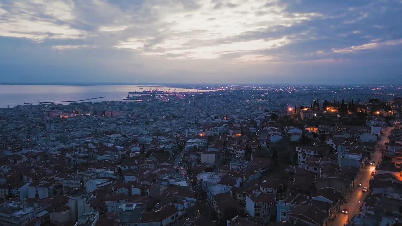 drone aéreo volando sobre el romántico casco antiguo de la ciudad de tesalónica por la noche iluminada, grecia, puerto al atardecer