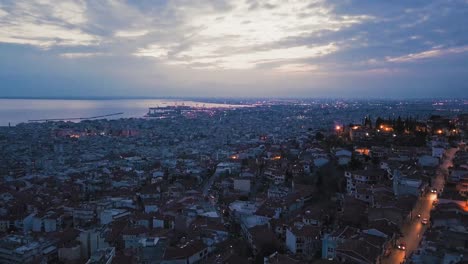 aerial drone flying over romantic old town city of thessaloniki by night illuminated, greece, port by dusk