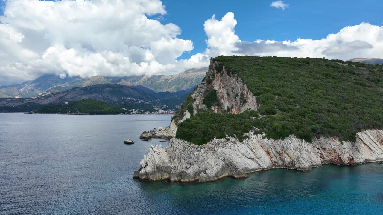 Wide tracking left ascend of Gjipe Beach cliffs and turquoise ocean under blue sky, aerial dolly forward