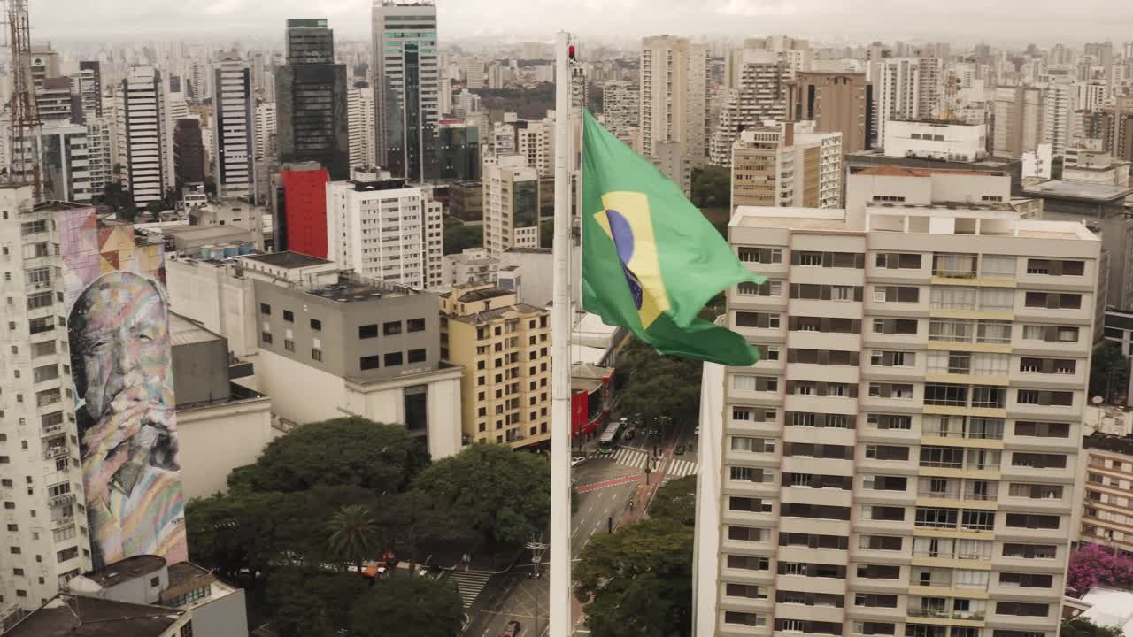 fotografía aérea de una bandera brasileña ondeando frente al centro de sao paulo durante un día de viento