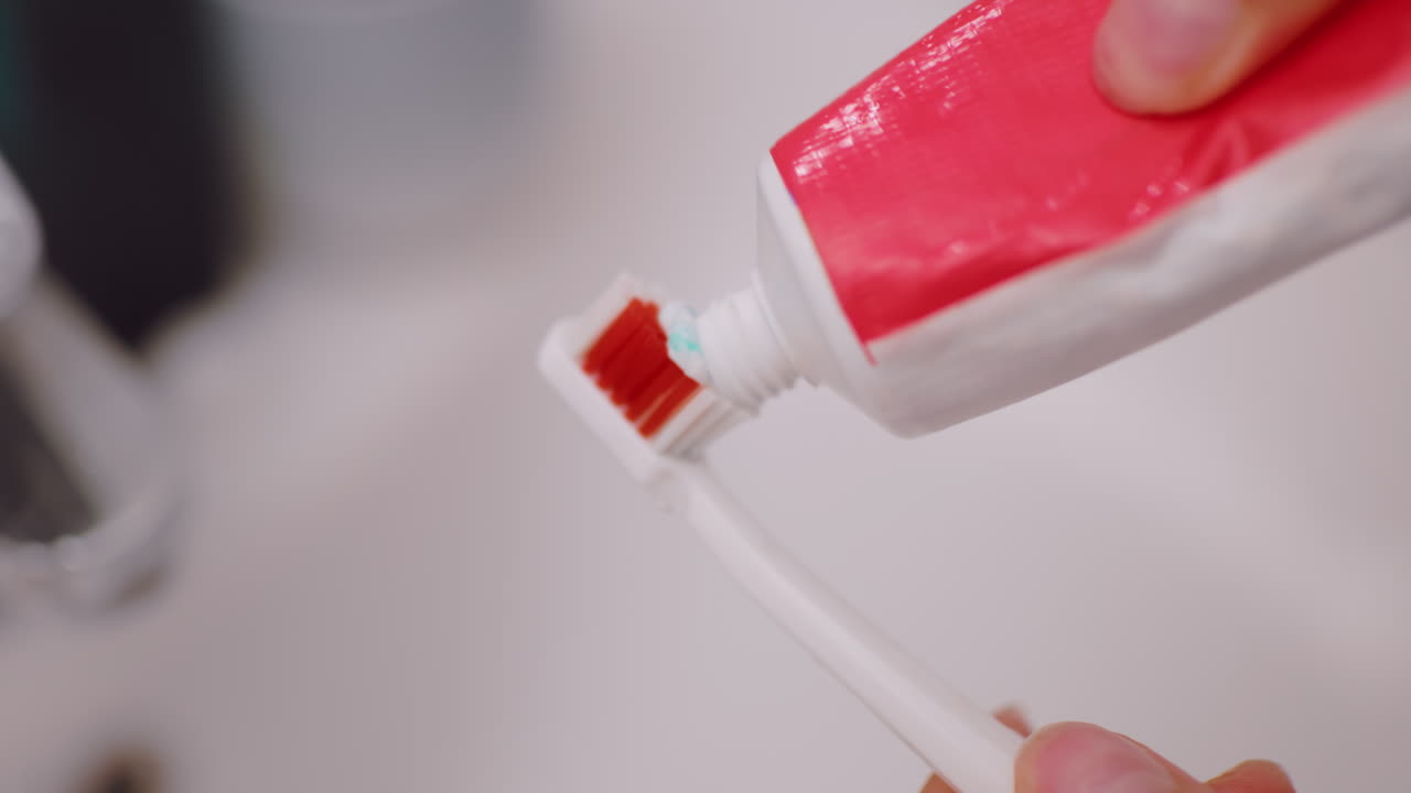 Close up of toothpaste being squeezed from tube onto toothbrush bristles in bathroom, focusing on oral hygiene, dental care, morning routine and personal grooming habits for healthy clean teeth