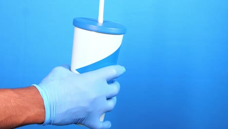 보호 장갑을 입은 사람이 으로 파란 컵을 들고 있습니다.