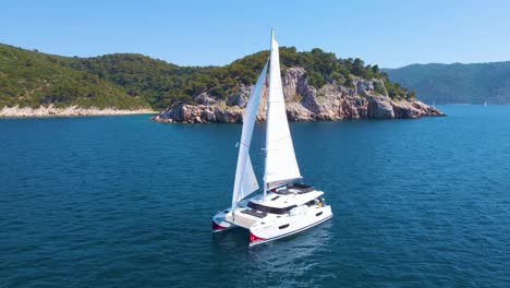 Drifting-yachts-in-the-bay-near-the-coastal-city-of-Croatia-against-the-backdrop-of-blue-skies-and-blue-transparent-water