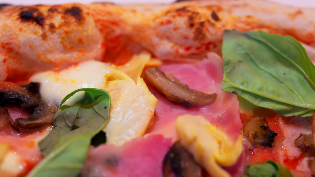 Close up of pizza with artichoke, ham, mushrooms and basil