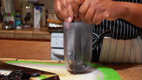 woman breaks up dried pepper and places in blender container, closeup